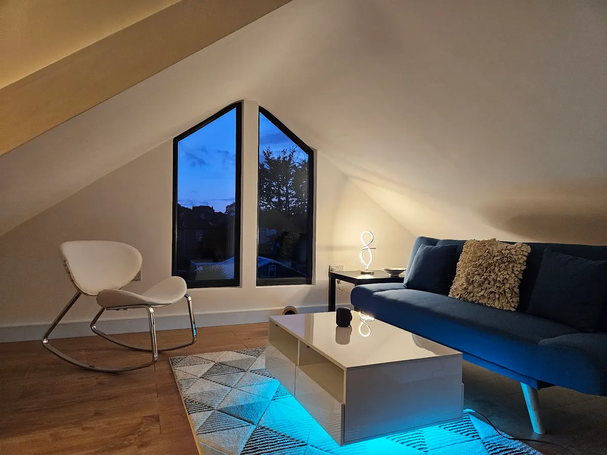Loft conversion living room at dusk with lit gable window